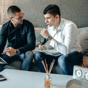Two businessmen discussing ideas with digital tablet and notepad in a stylish office.
