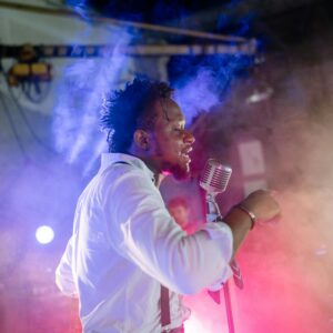 Dynamic live performance by a male musician with vintage microphone under colorful stage lights.
